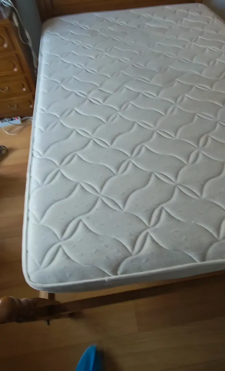 Colchão branco de casal pousado na estrutura da cama, antes do serviço
