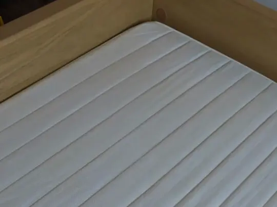 Colchão branco acolchoado, limpo, numa cama de madeira