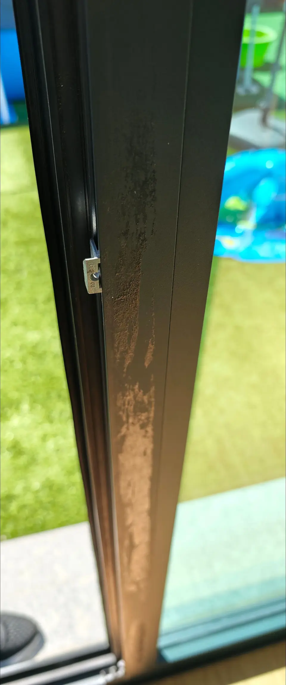 Pormenor de um caixilho escuro com pó de obra agarrado
