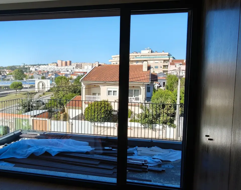 Janela larga de um quarto, com o vidro limpo e o terraço lá fora
