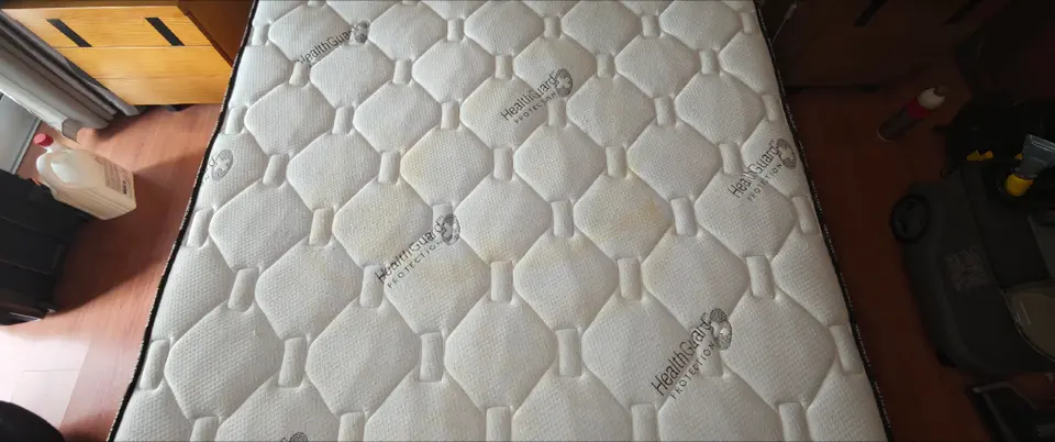 Colchão branco acolchoado com manchas amarelas, antes da limpeza